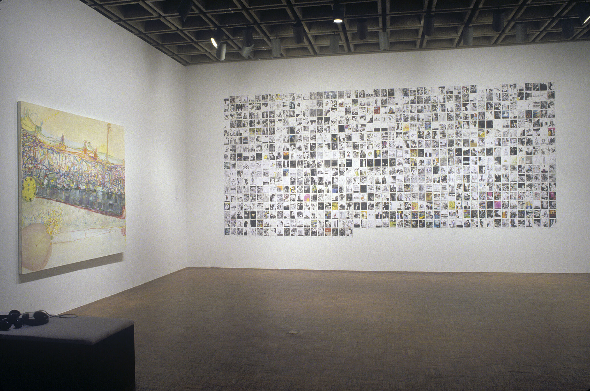A gallery wall filled with tiny drawings that create a grid, along with a large painting displayed on another wall.