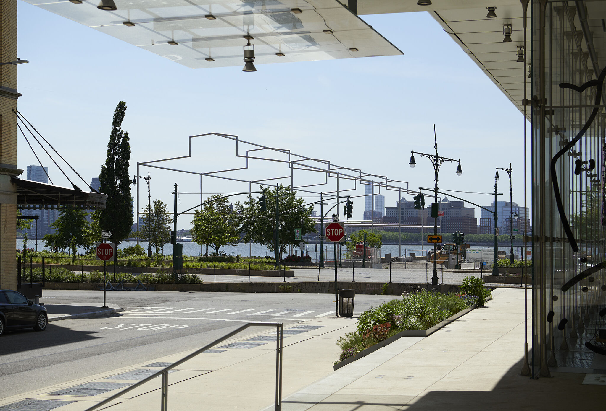 View of Day's End steel sculpture from the Whitney Museum in broad daylight, with New Jersey skyline in the background.