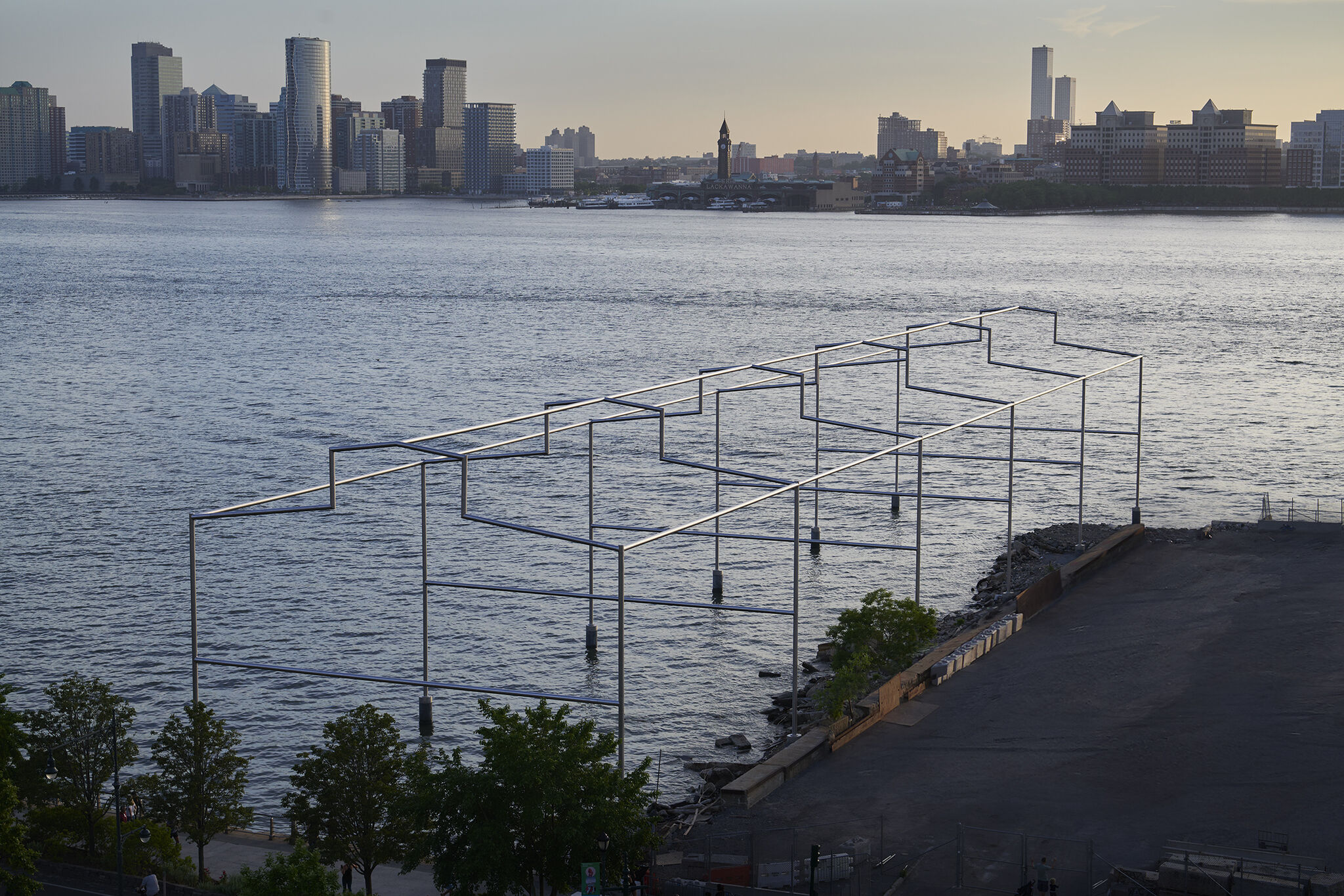 Overhead view of Day's End steel sculpture on the Hudson river at sunset, with New Jersey skyline in the background.