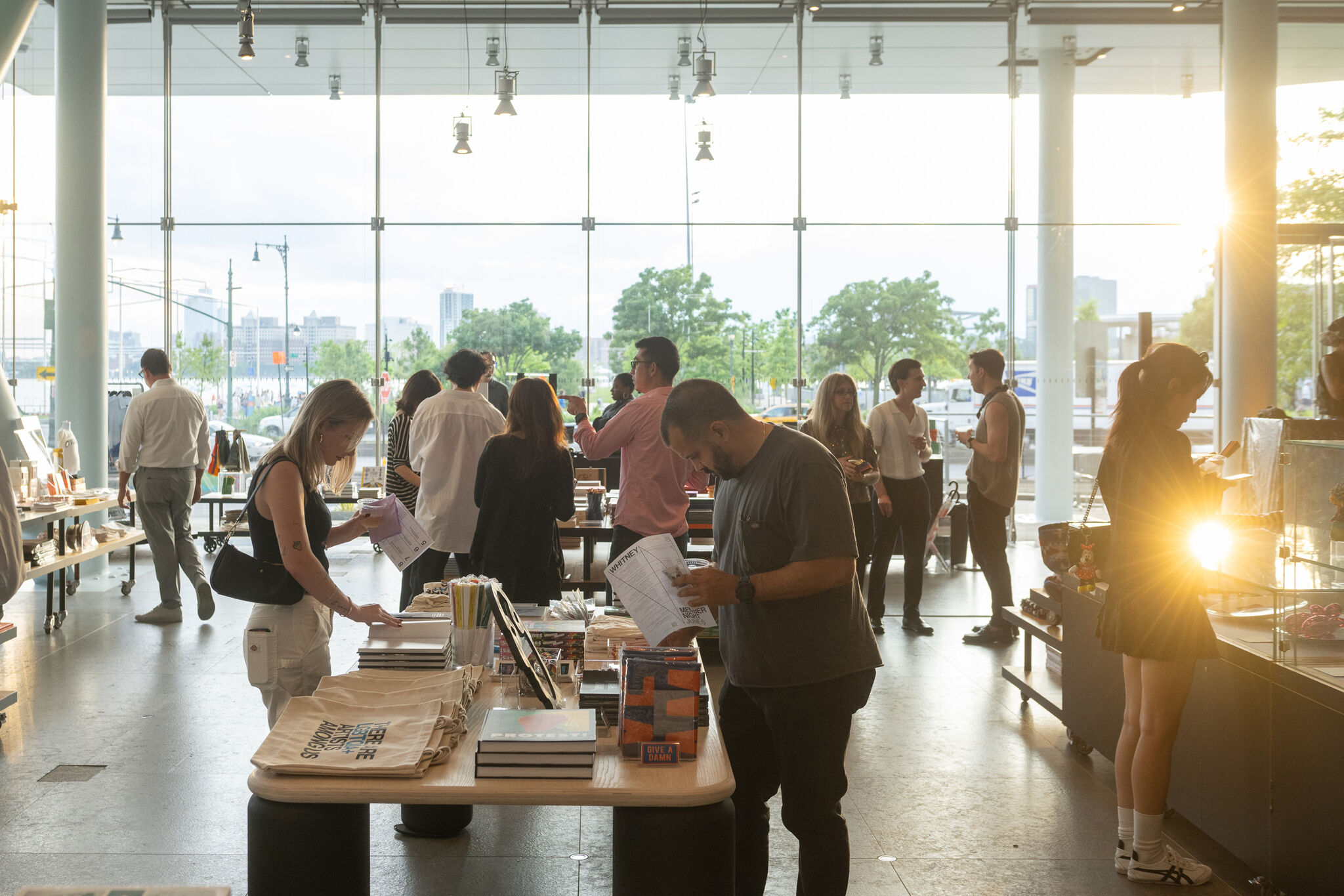 Members in the Whitney Shop looking at items laid across low tables and in glass cases.