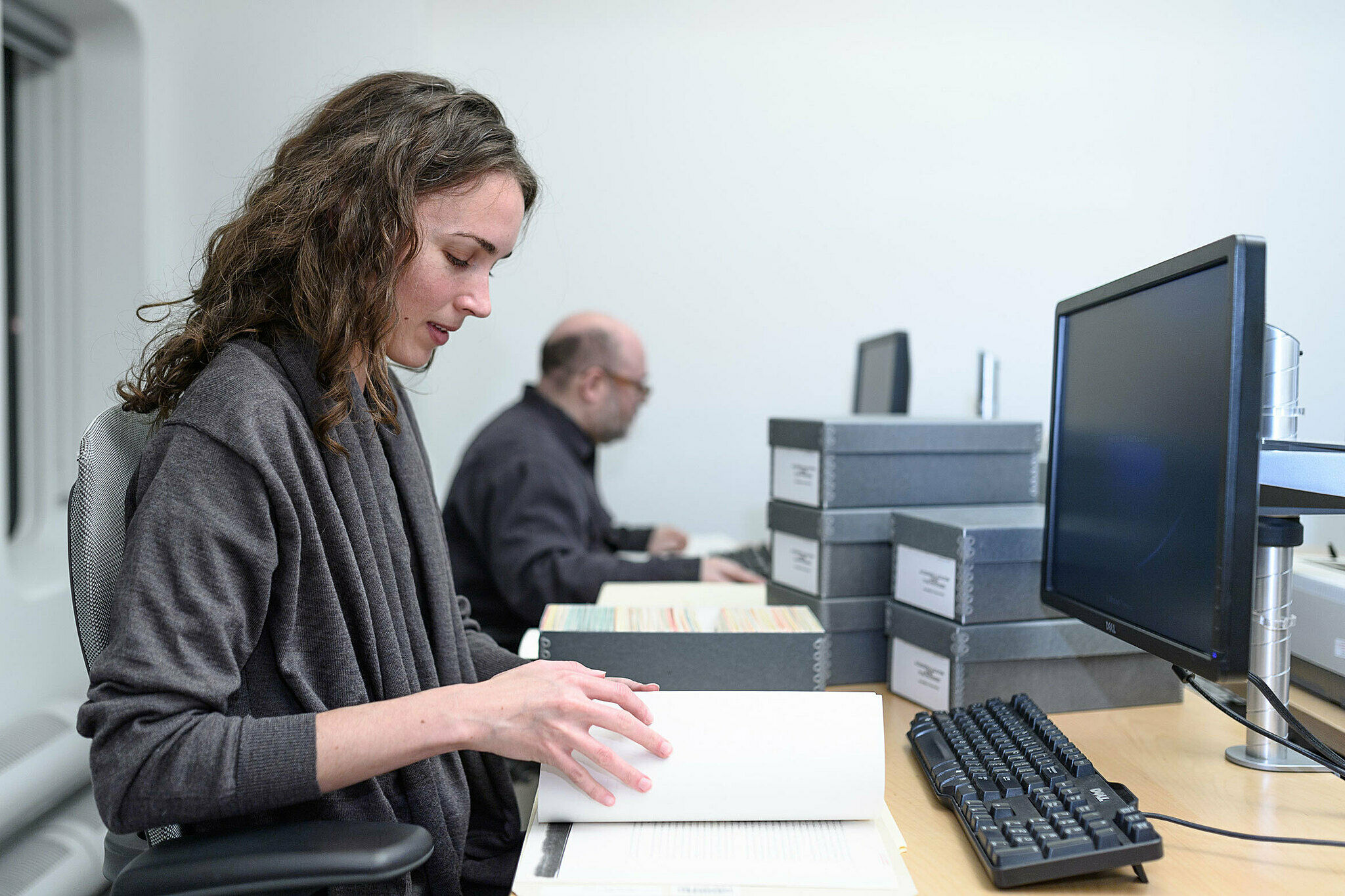 Woman looking through a book in an archive.