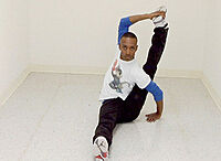 A men stretches his leg behind his body while sitting down.