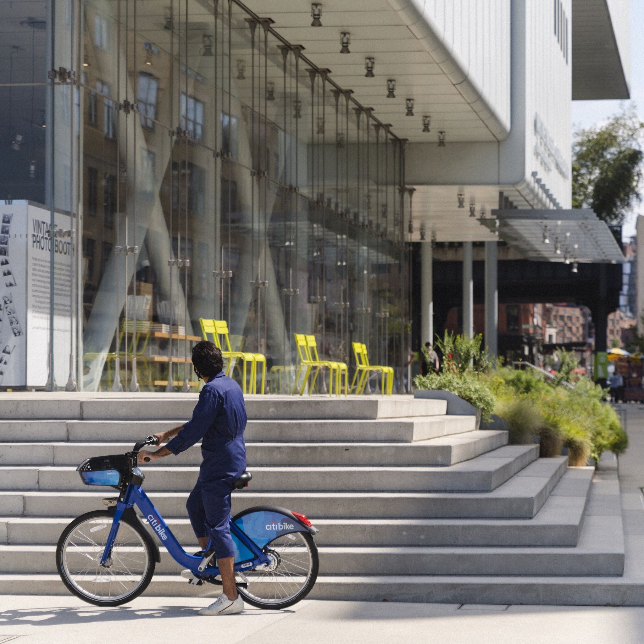 A person on a bike stands outside the Whitney Museum. 