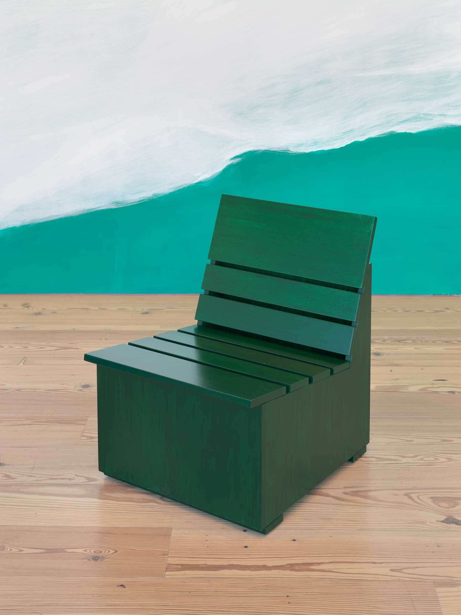 A dark green wooden chair with a slatted seat and backrest sits on a light wooden floor.