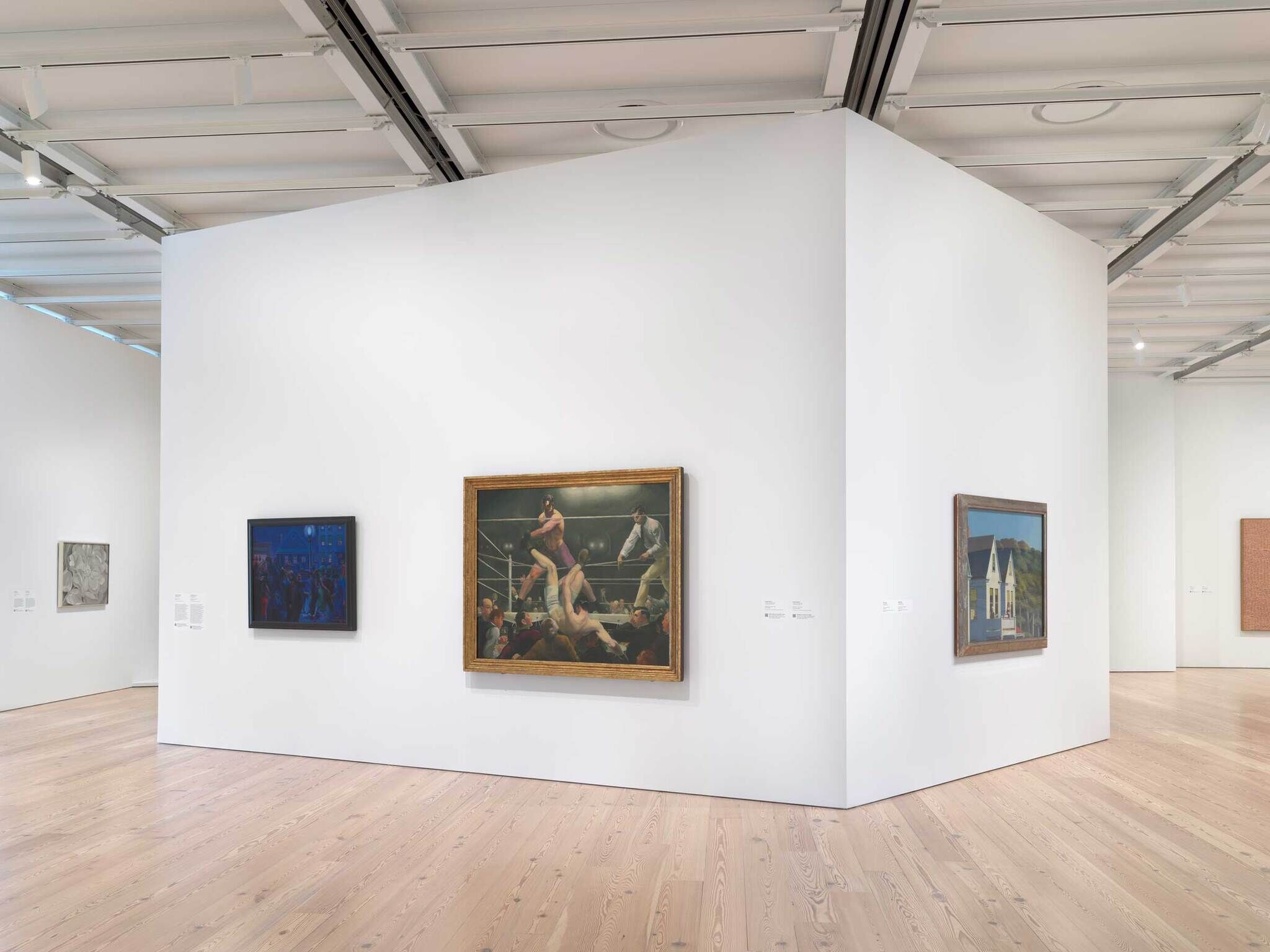 Several paintings hang on white gallery walls, including a boxing match scene and a house with a porch.