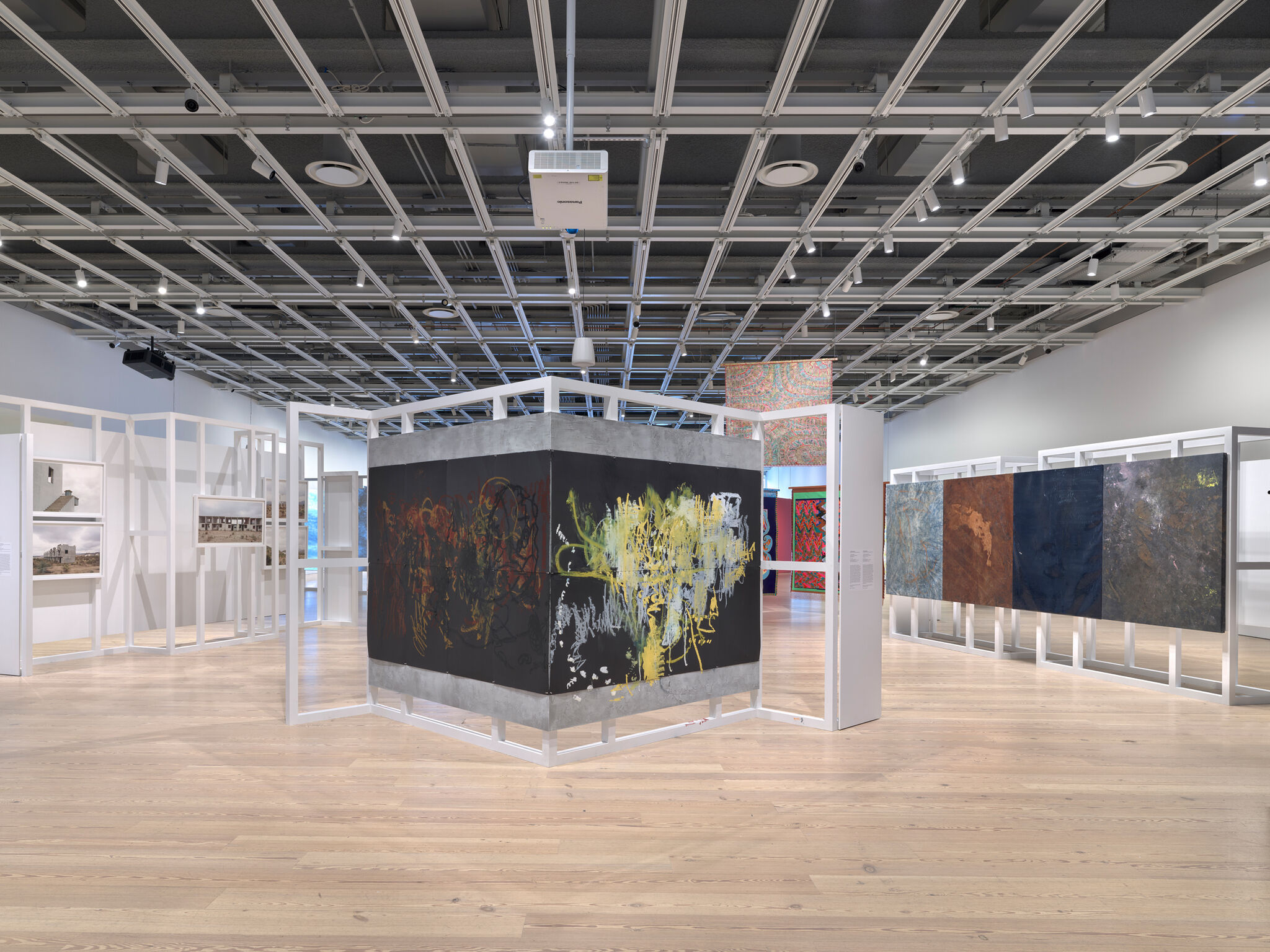 Multiple abstract artworks in a light-filled gallery.