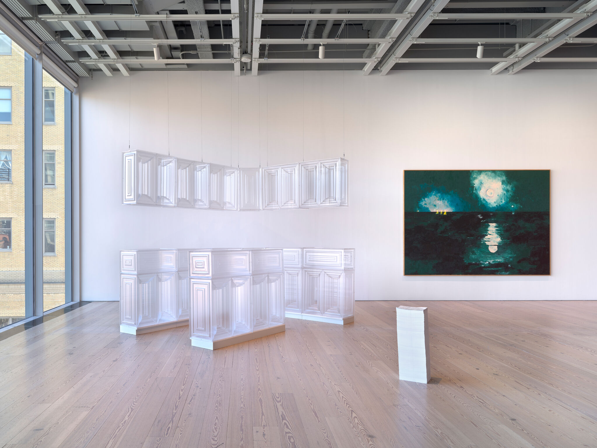 Three artworks to the right of a large gallery window.